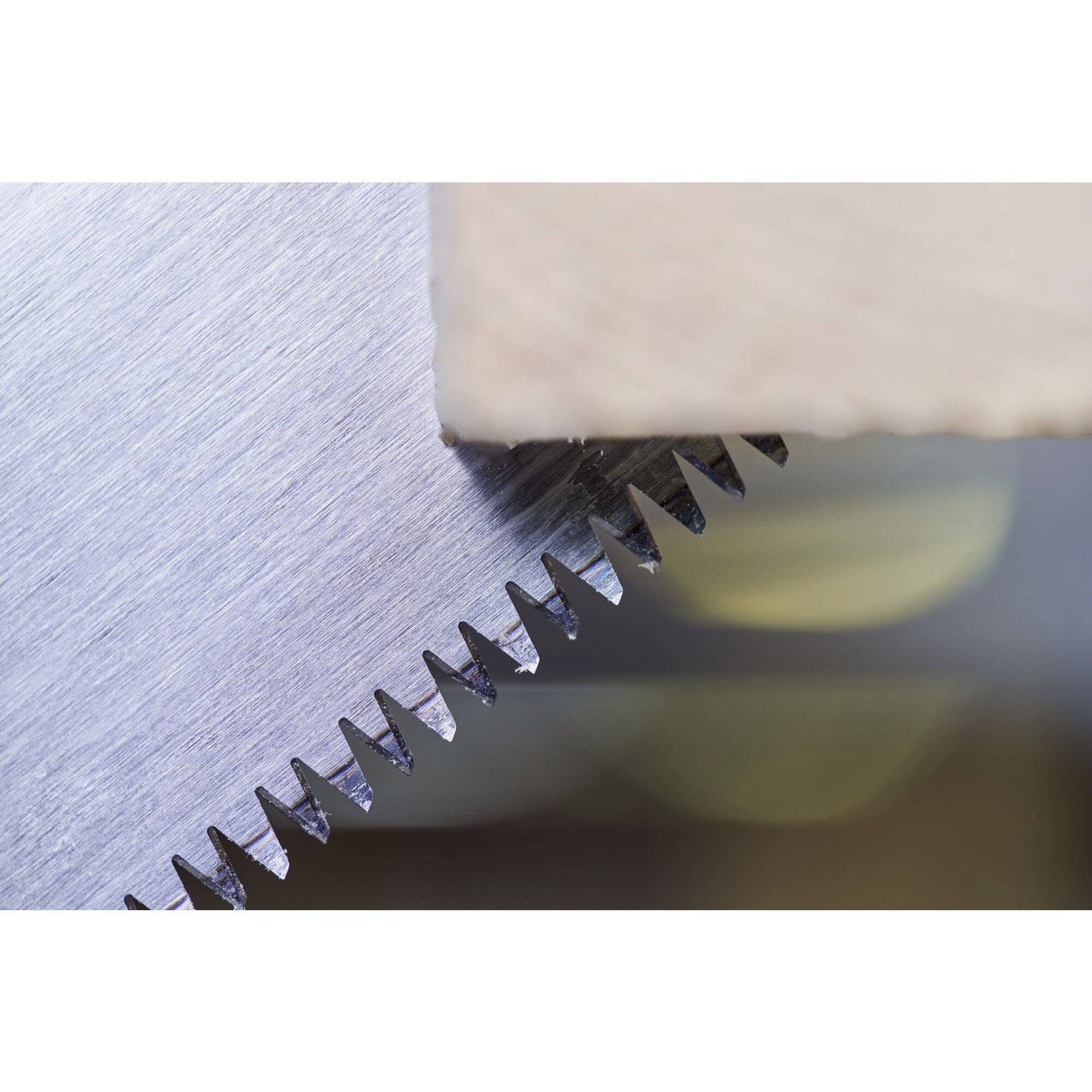 Close-up of sharp, metallic saw teeth biting into a piece of wood. Focus is on the serration and material contrast.