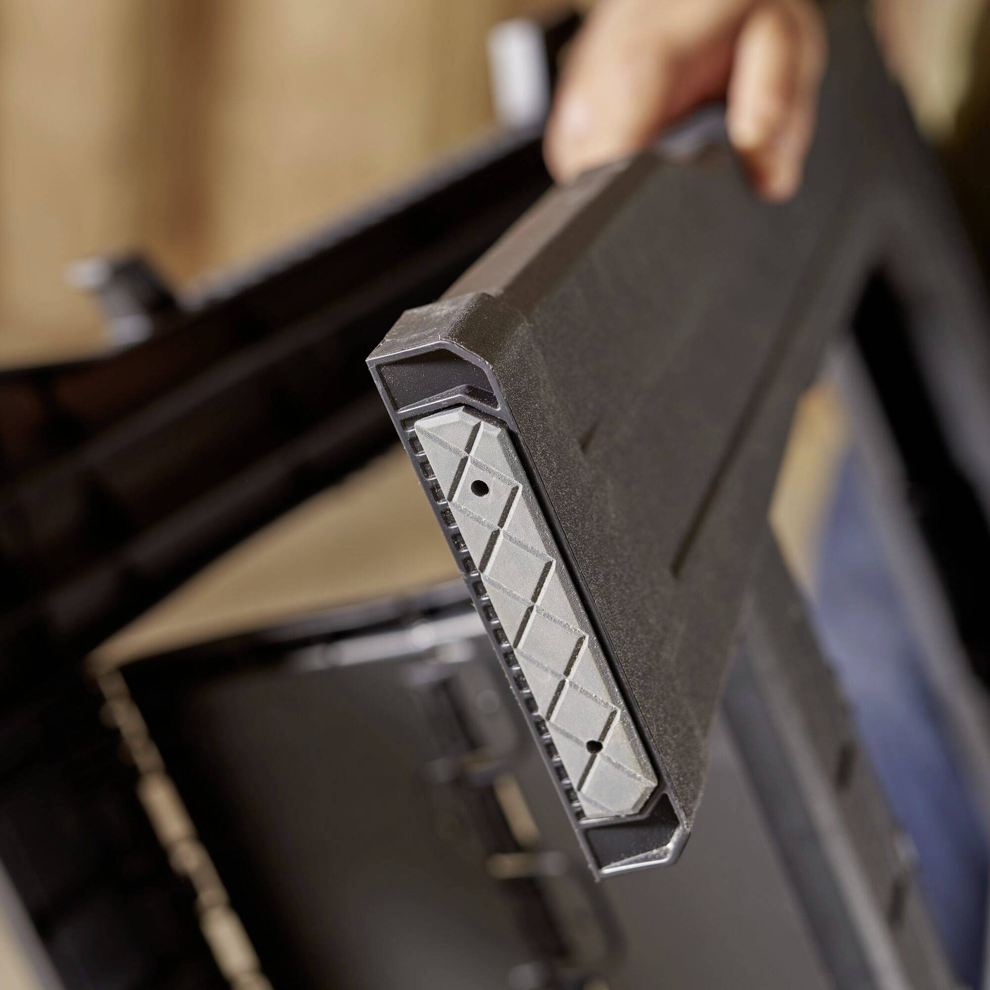 A person is holding a rectangular object with a honeycomb-like structure at the edge, possibly a tool or equipment case.