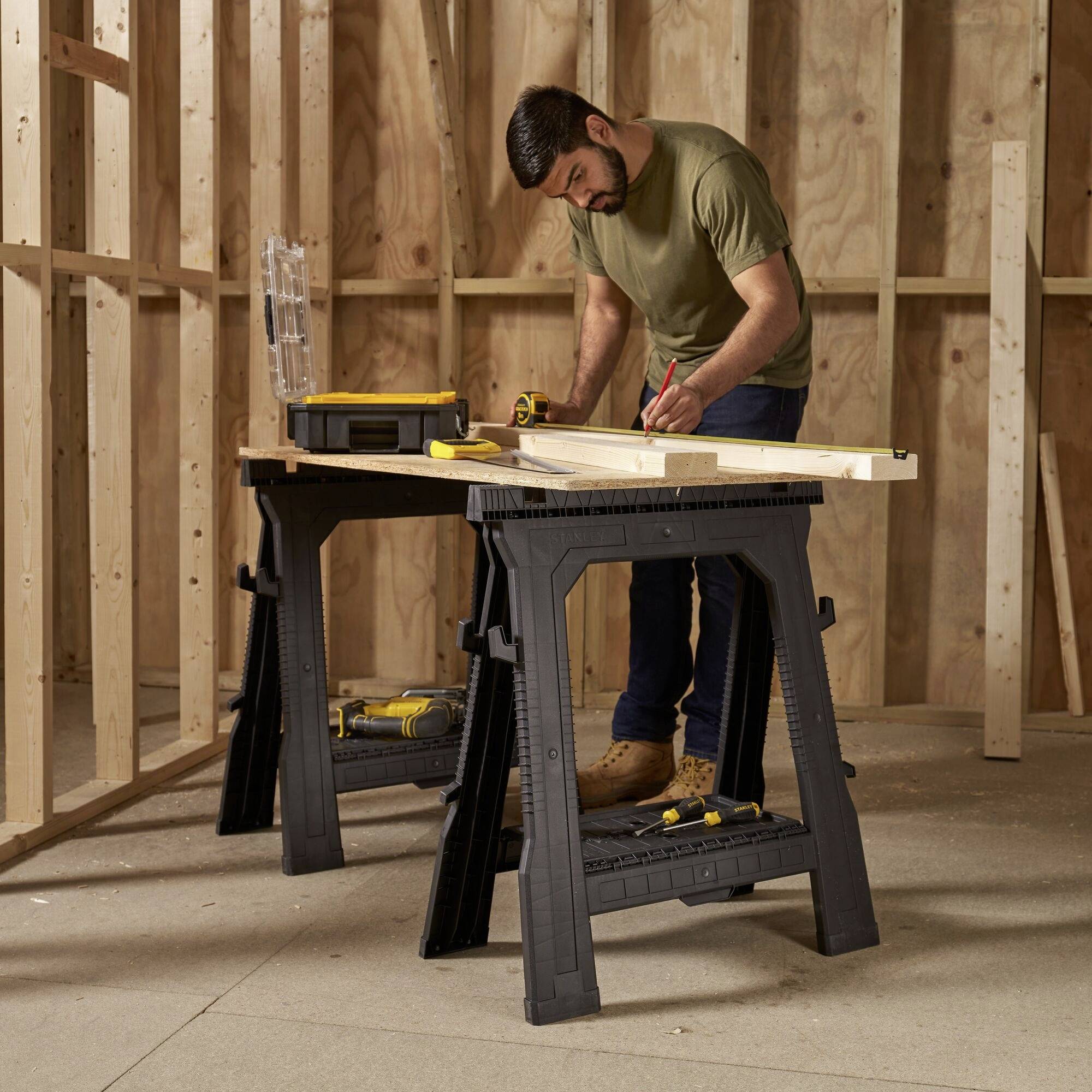 A man is working on a wooden beam on a sawbench in a timber construction environment under development.