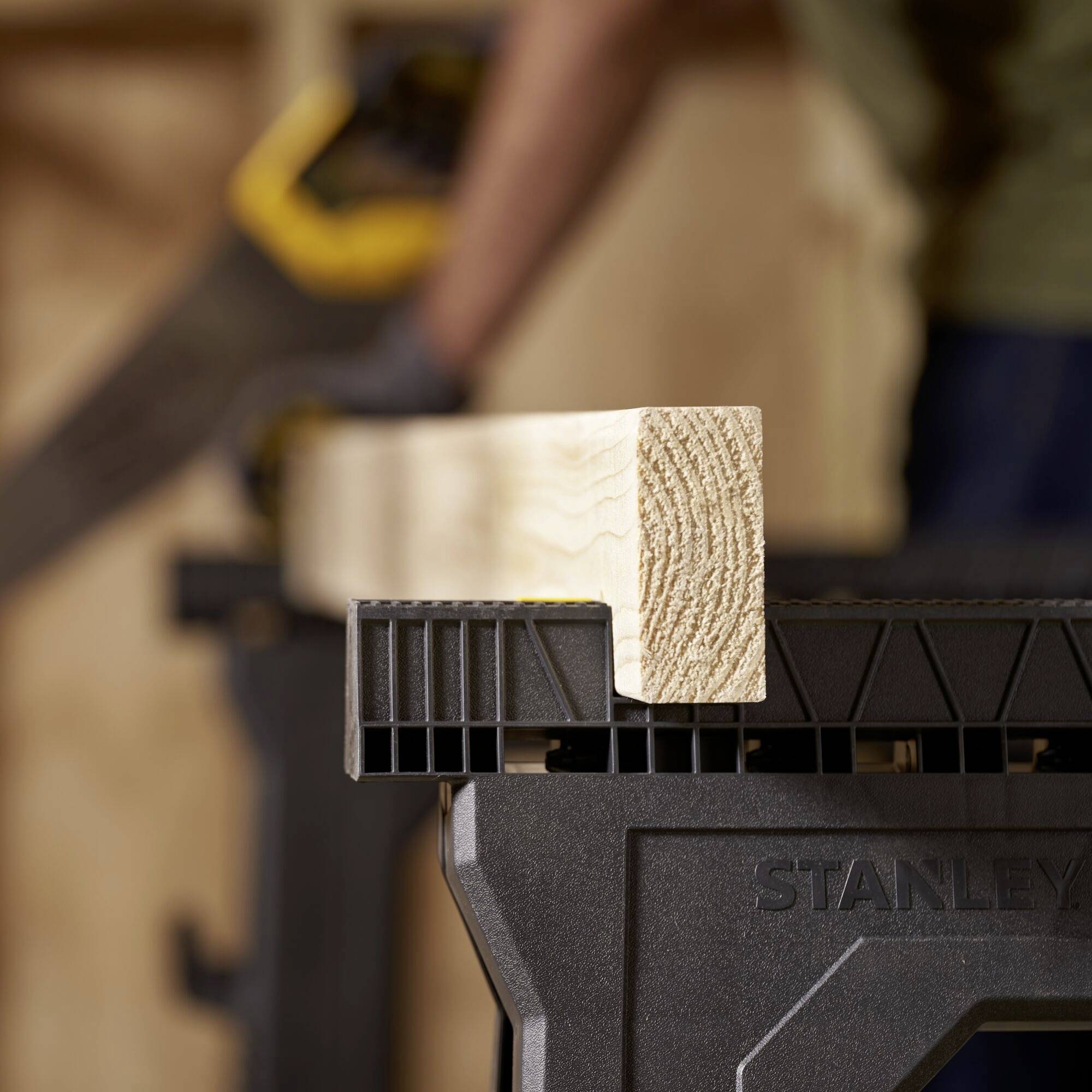 A craftsman cuts a piece of wood with a saw on a workbench. The wood is being cut precisely in a workshop scene.