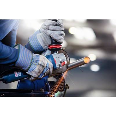 A person is grinding a metal pipe with an angle grinder, sparks flying. Protective clothing and gloves are being worn.