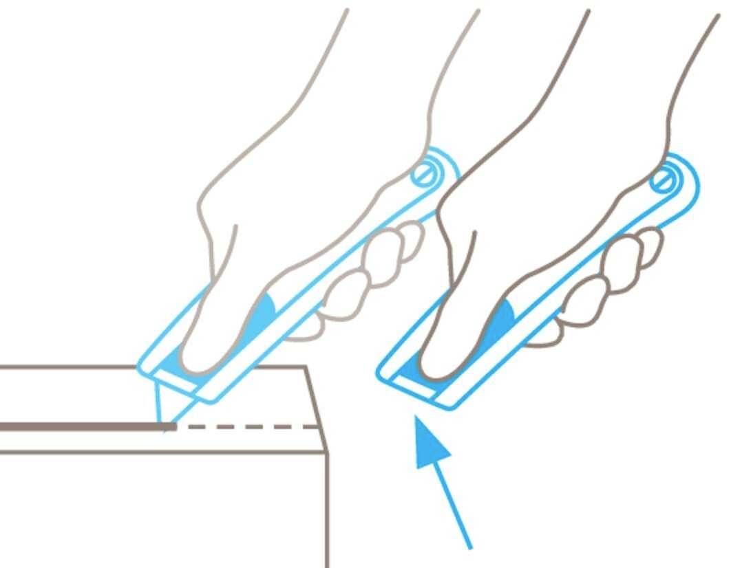 Two hands are using a cutting tool to open a cardboard box along a dotted line.