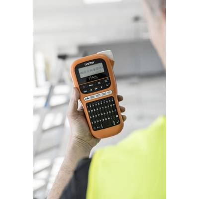A person is holding an orange labelling device with a display and keyboard. A ladder is blurrily visible in the background.