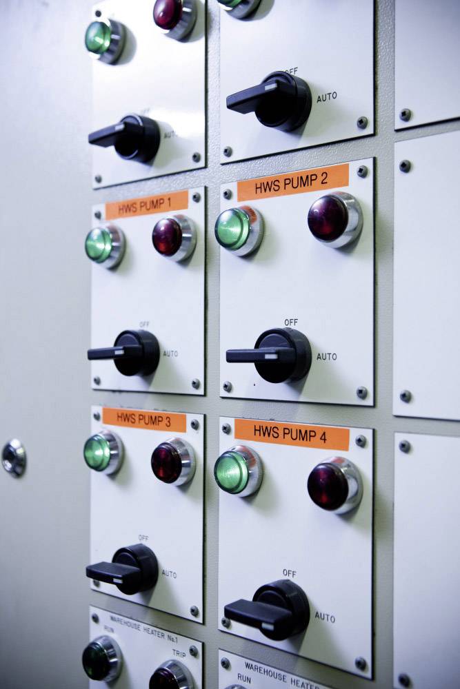 Control panel with multiple switches and lights, marking pump control. Labels show 'HWS PUMP 1-4'. Switches set to 'Auto' or 'Off'.