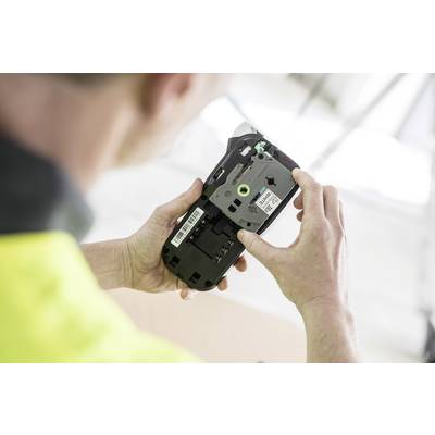 A person is holding an open electronic device, seemingly for inspection or repair, with wires and barcode labels visibly present.