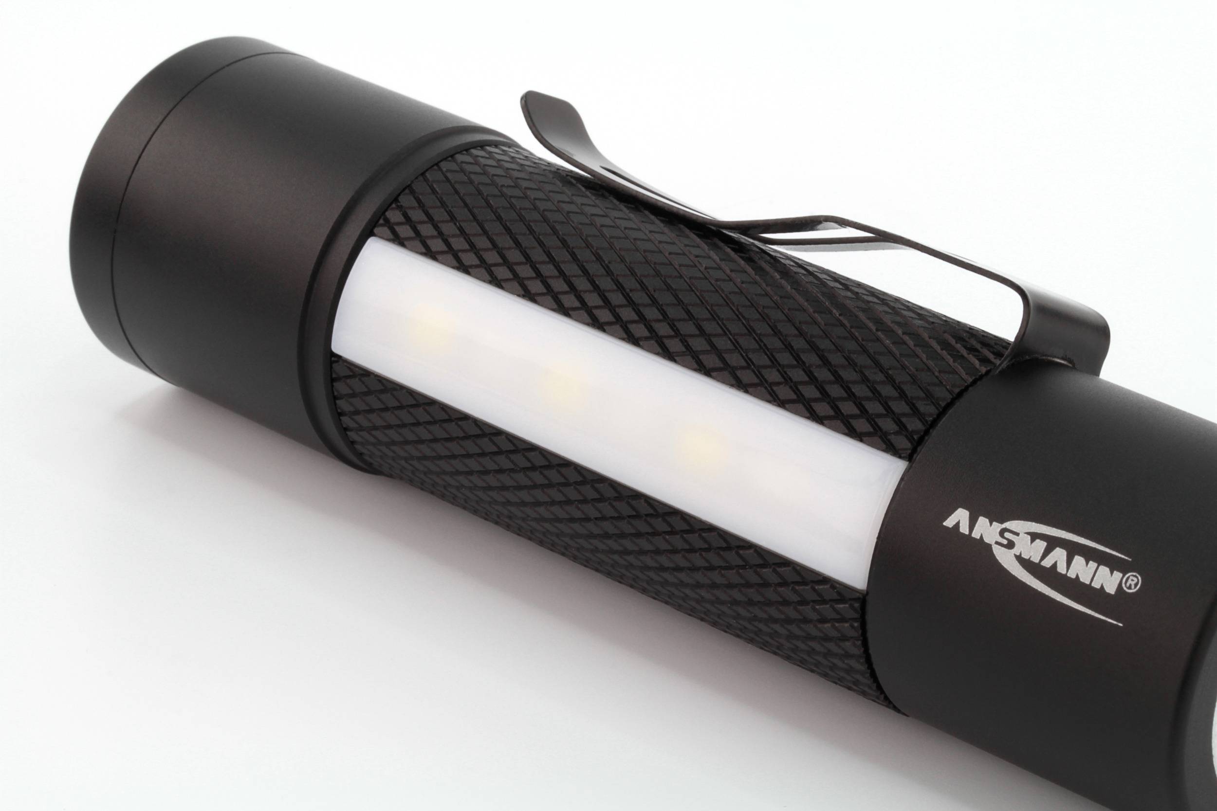 Black torch with textured grip and clip, white illumination area, brand name 'ANSMANN' visible.