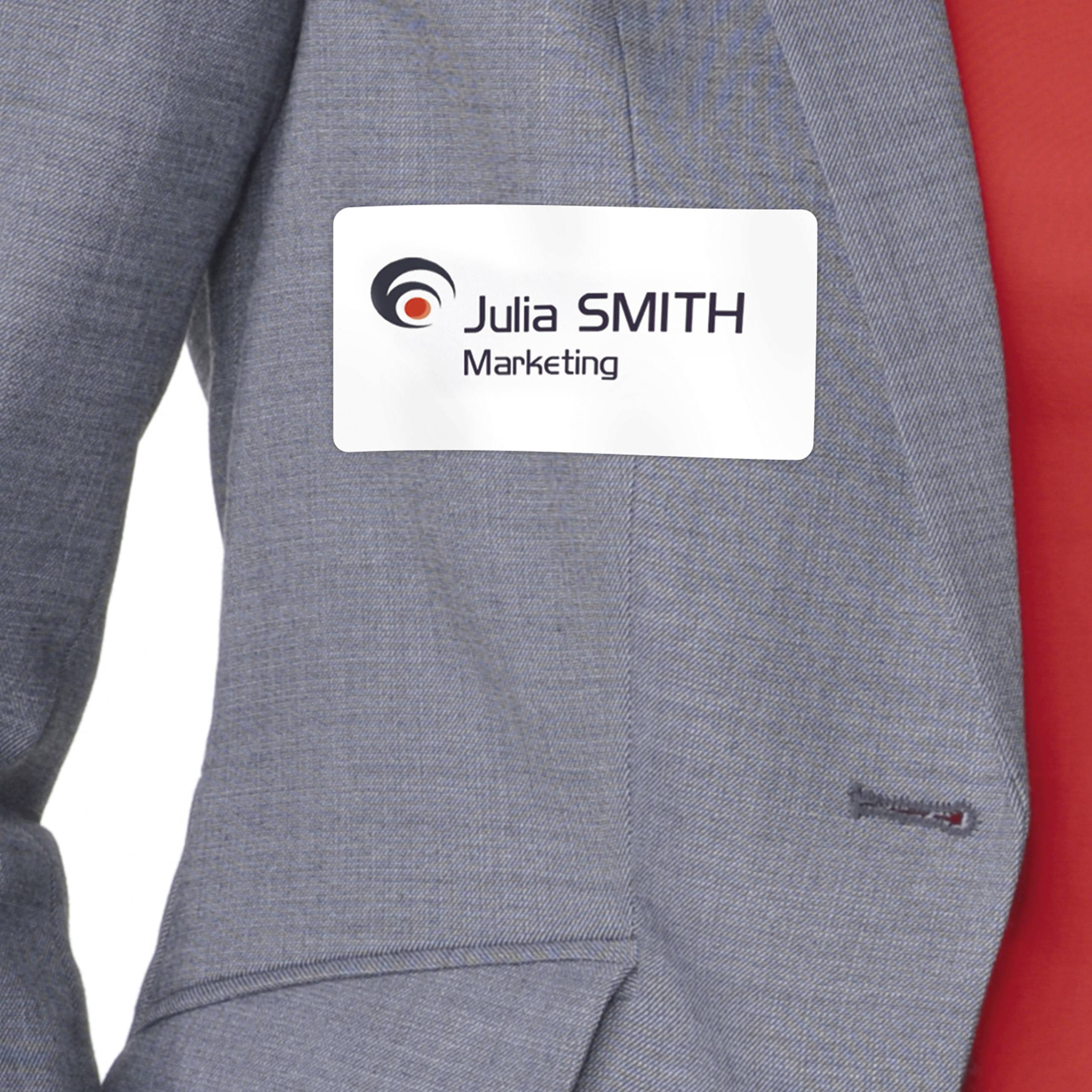Woman in a grey blazer wearing a name badge 'Julia SMITH, Marketing' on her chest, against a neutral background.