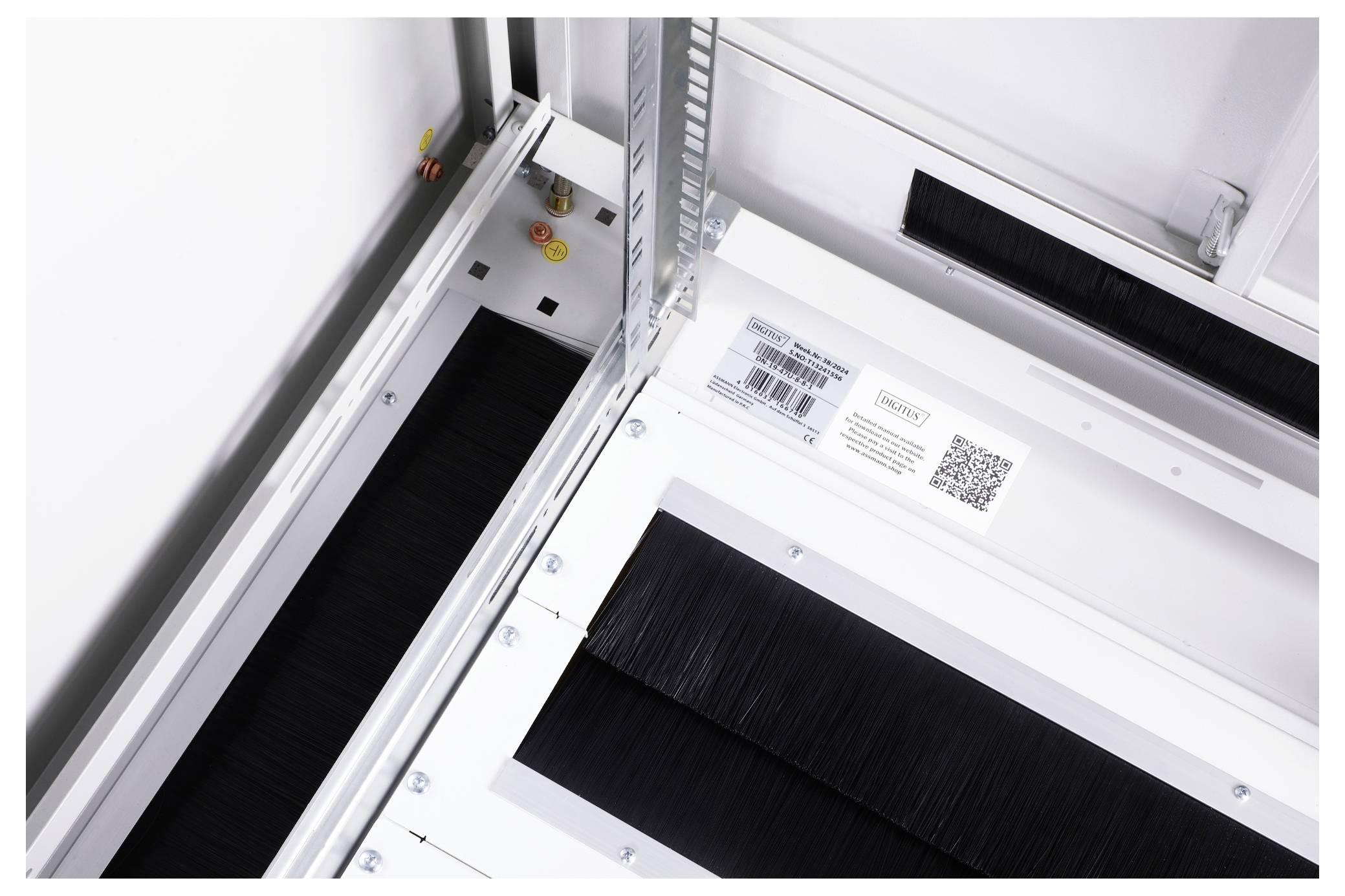 View of the inside of a white technical device, with black brush elements and a barcode sticker.