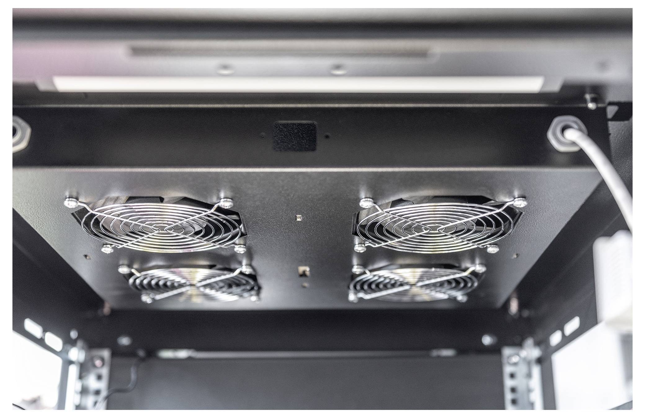 'Bottom view of a metal ceiling vent system with four circular fans, each protected by a metal grille.'