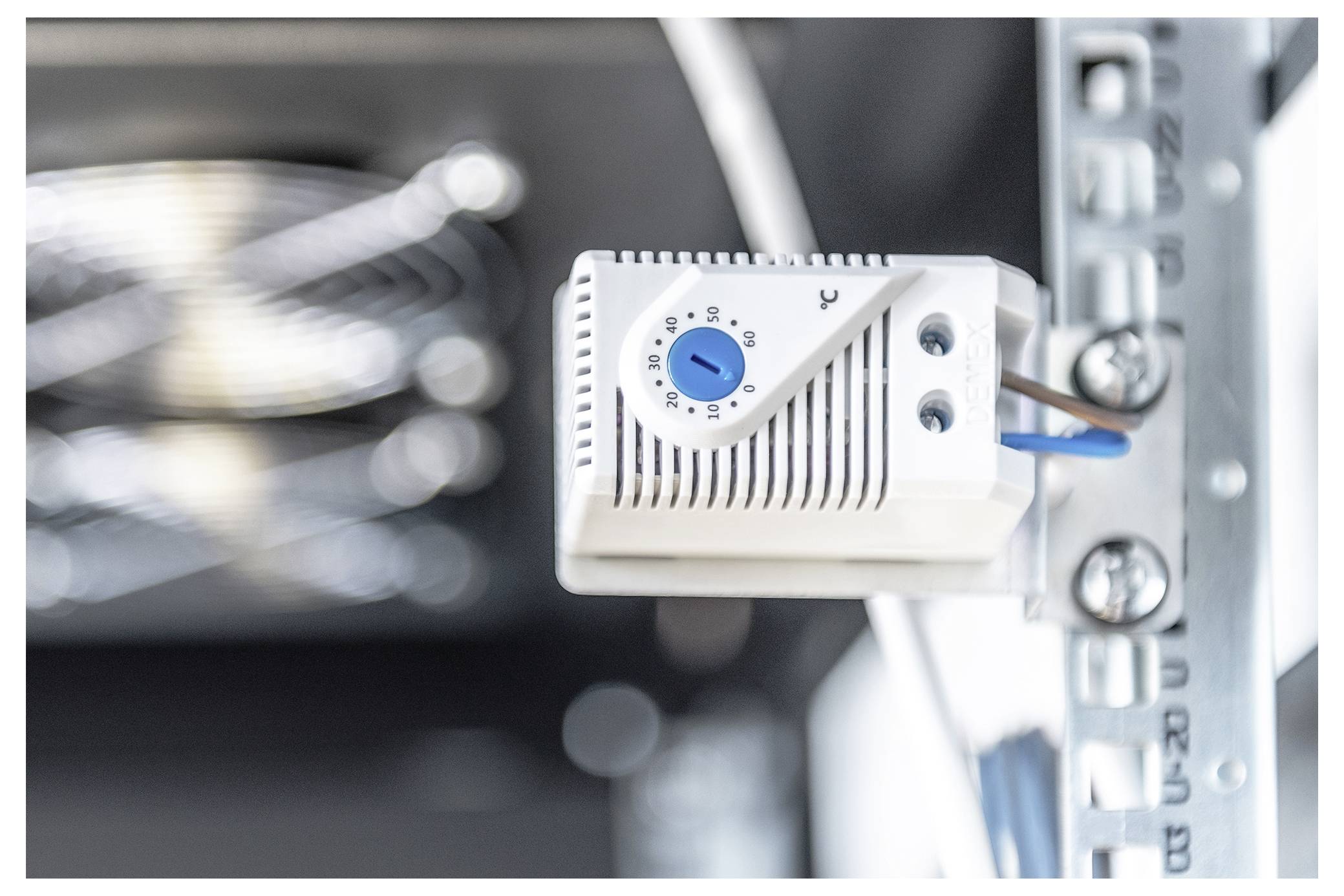 A temperature control device with a blue dial is mounted on a metal frame, indicating a system for regulating environmental conditions.