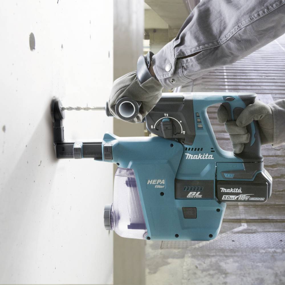 A person is drilling a hole in a white concrete wall using a blue, battery-powered drill hammer.
