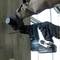 A person is drilling a hole in a concrete wall using a Makita drill hammer. Windows are visible in the background.