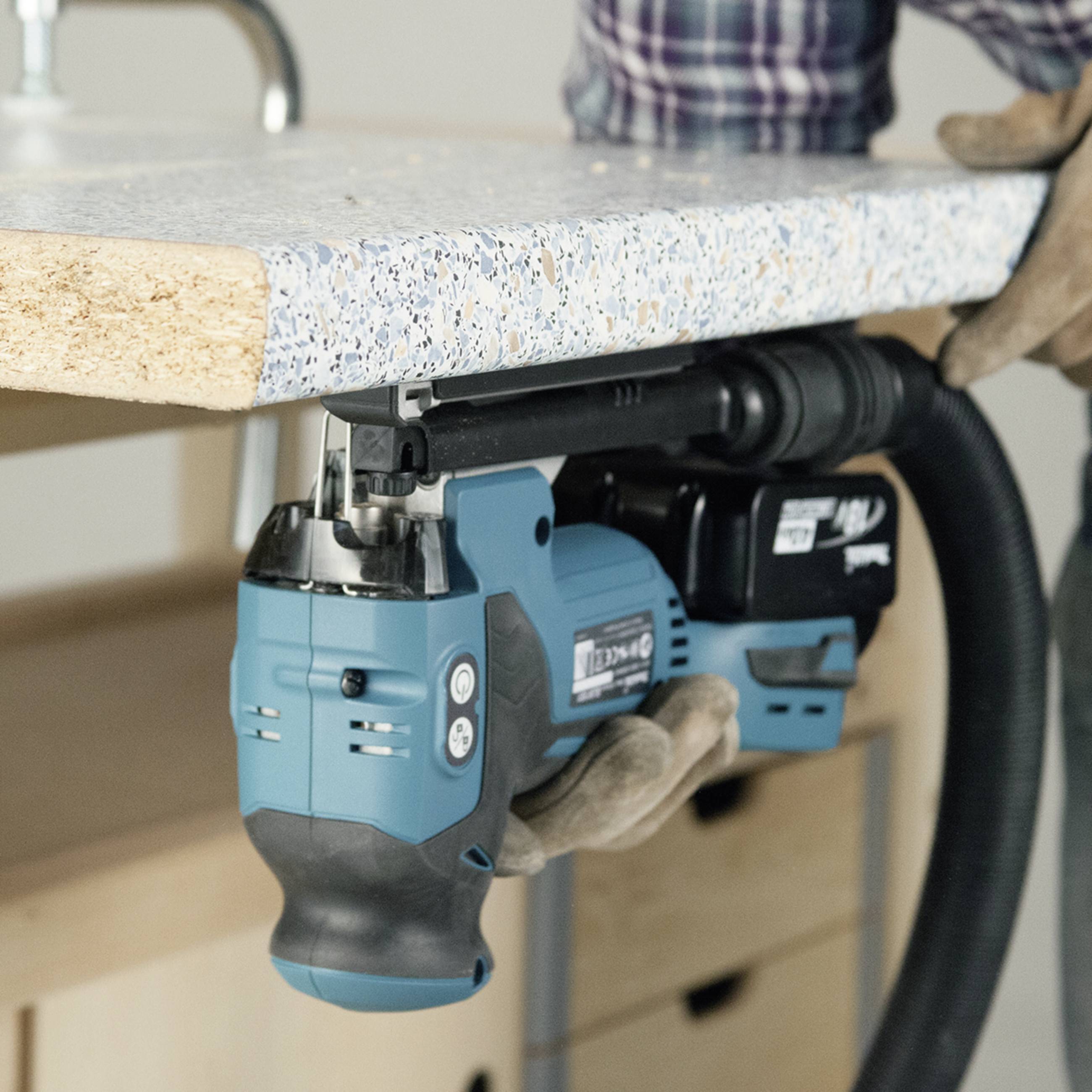 A person is working with an electric handsaw at a workbench. The saw is cutting through a wooden board.