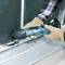 A person is working on a window frame with a blue multi-purpose tool. They are wearing gloves and a checked shirt.