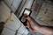 A hand is holding a laser distance measuring device, which displays '8,602 m'. It is being used to measure the distance of a wall in a construction site environment.