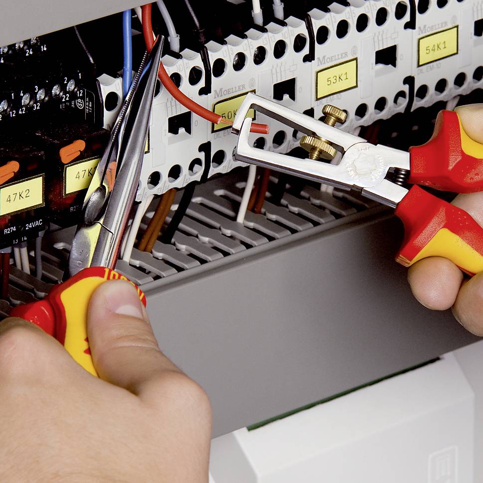 A person repairs an electrical junction box with pliers and a screwdriver, focusing on cable connections and fuses, demonstrating technical work.
