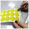 A person uses a hole punch to mark yellow safety inspection stickers labeled with months and years, indicating a recent check.