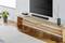 Wooden bench with decorative items, including books and candles, positioned in front of a flatscreen television mounted on the wall. A speaker placed beneath it.