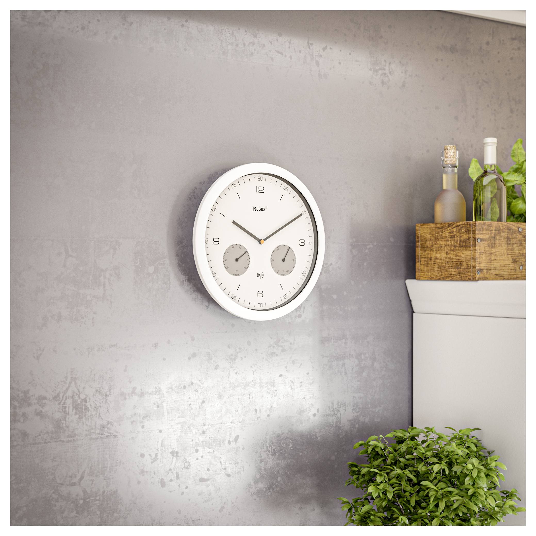 A clock with two smaller dials for day and month is mounted on a textured gray wall, next to a cabinet holding bottles and potted plants.