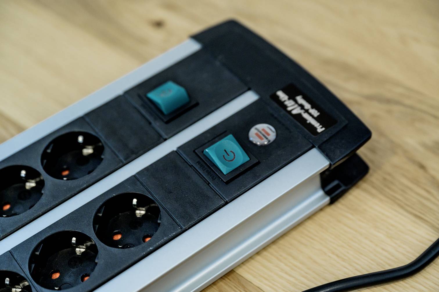 Multi-socket extension with five sockets and two switches on a wooden table.