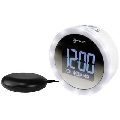 A digital alarm clock with a large, blue display shows '12:00'. A circular vibrator connected to the alarm clock lies beside it.