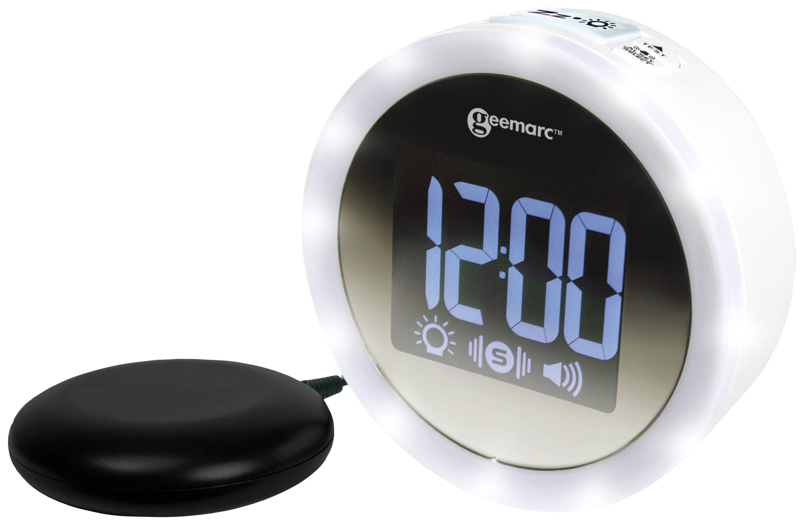 Digital alarm clock with large, blue digits '12:00'. Next to the alarm clock lies a black, round device, presumably a vibration cushion.