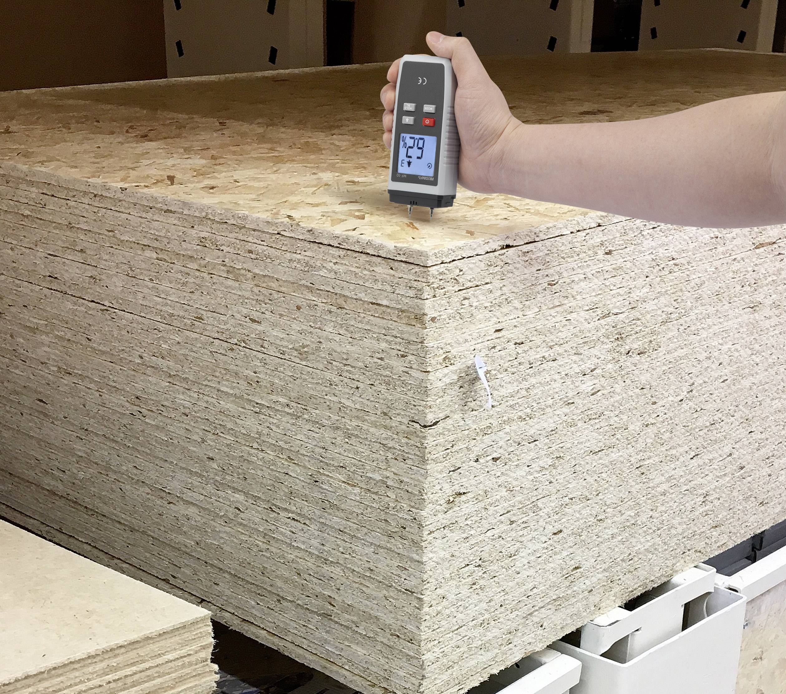 A stack of wooden boards is being checked with a moisture metre. The device indicates 7.9 percent moisture.