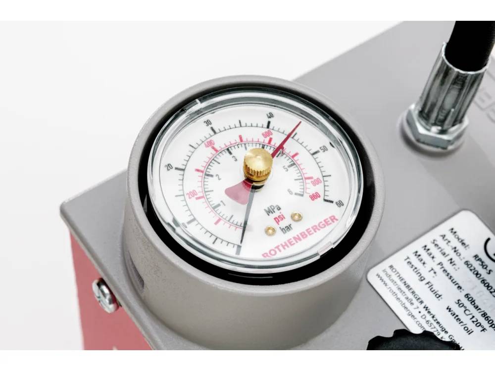 Pressure gauge on equipment showing a reading in bar and psi, labeled 'Rothenberger', with control knob and informational sticker nearby.