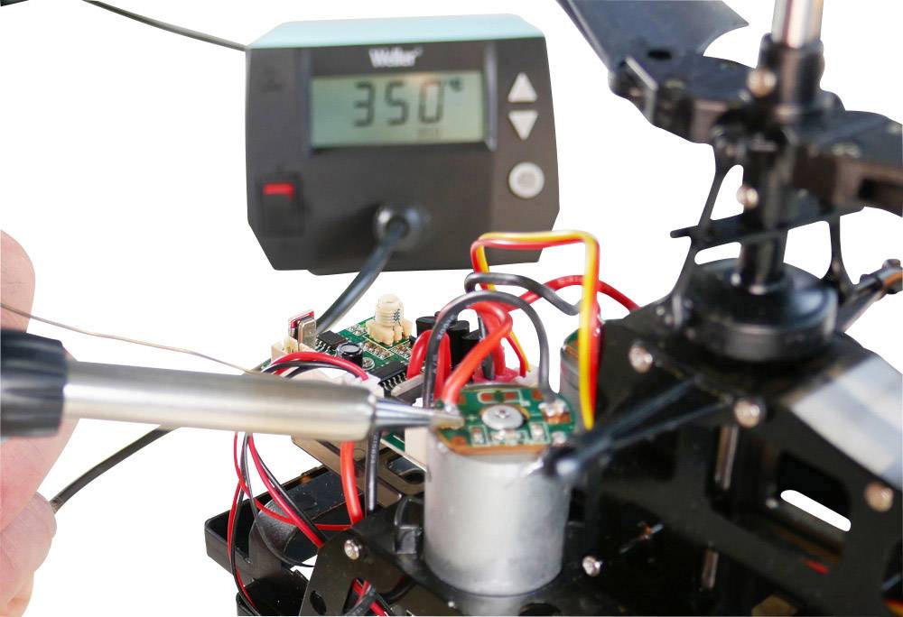 'Soldering iron on a circuit in a technical setup, with a thermometer showing 350°C; focus on precision and temperature control.'