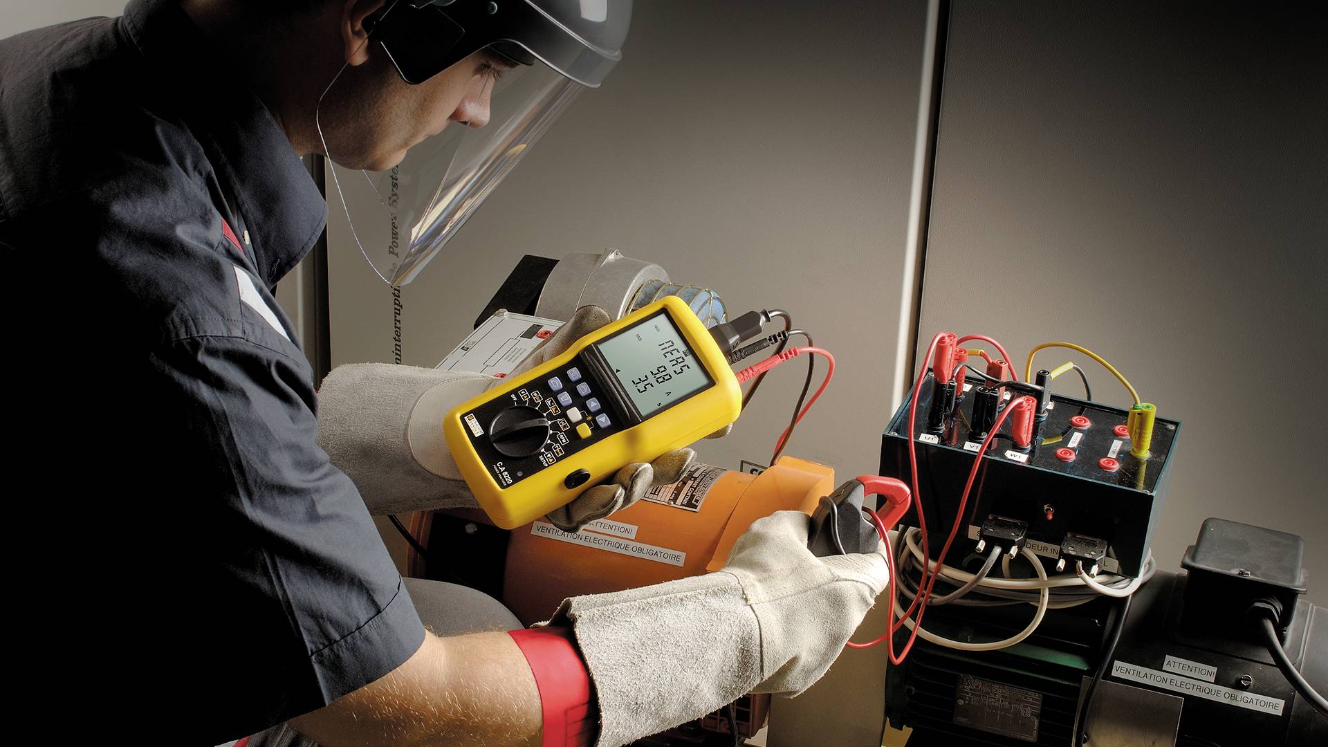A technician wearing protective equipment checks the voltage of an electronic device with a multimeter; safety in focus.