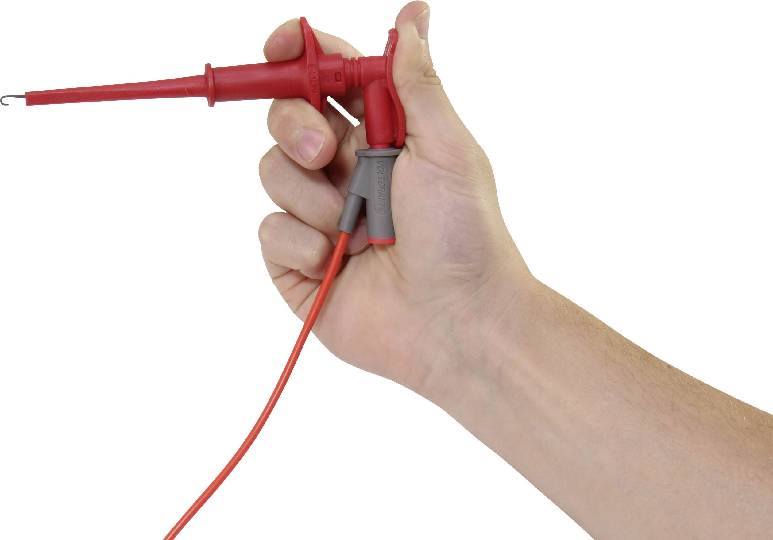 A hand is holding a red test probe with a cable, used for electrical measurements.
