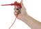 A hand is holding a red test probe with a cable, used for electrical measurements.