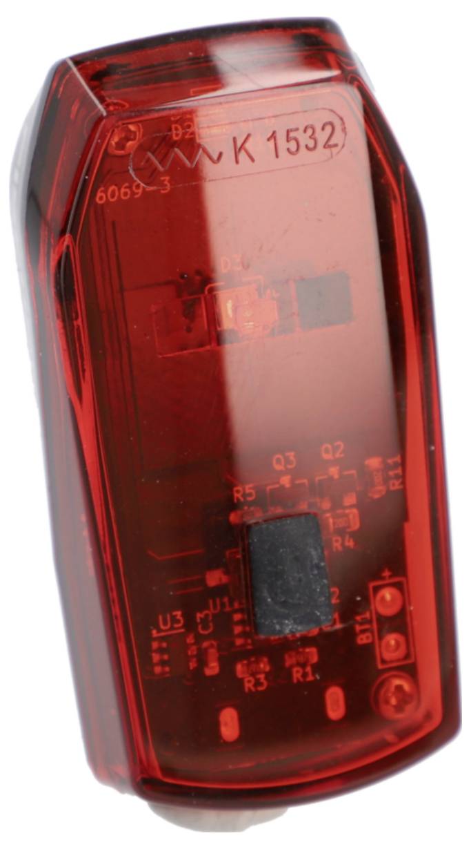 A rectangular, red transparent plastic bike light with visible internal electronic components.