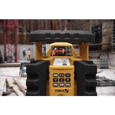 'Close-up of a yellow laser level on a construction site. Builders and equipment working out of focus in the background.'