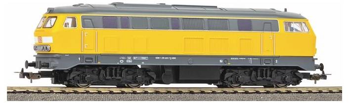A model train with a yellow and gray locomotive on tracks, featuring detailed windows and wheels.