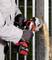 A person is grinding metal with a red angle grinder, sparks flying. The person is wearing protective clothing and gloves.