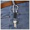 A carabiner attached to a belt loop of blue jeans holds two metal keys.