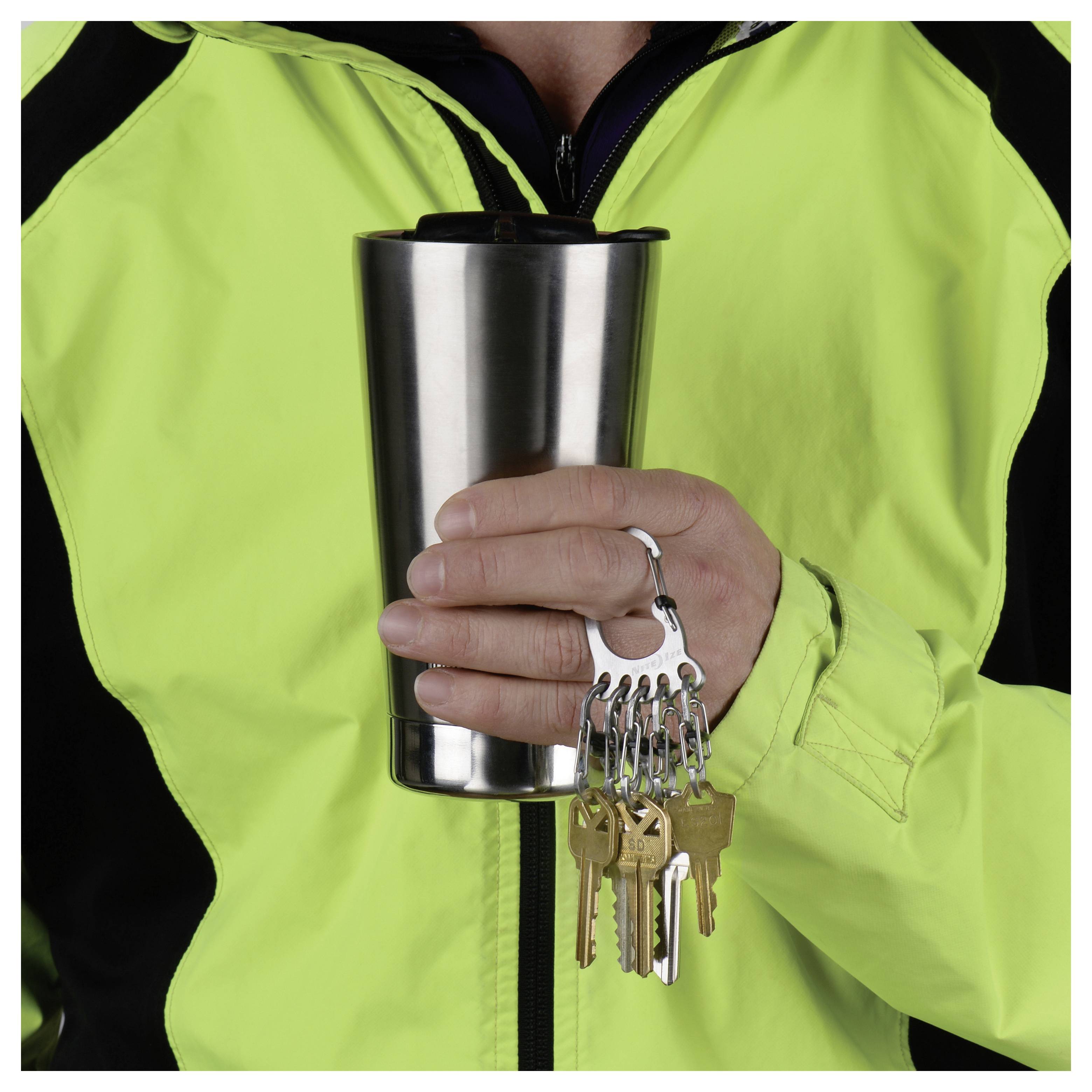 A person in a high-visibility jacket holds a stainless steel travel mug and a keyring with several keys attached.