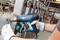 A person is holding a Bosch hot air blower and working on a technical component in a factory environment.