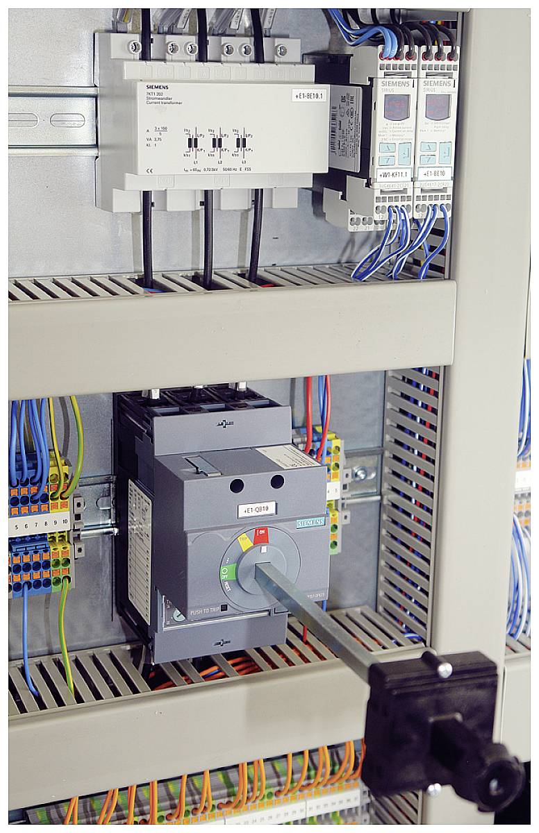 An open electrical cabinet reveals wiring and electrical components such as fuses and switches for controlling electrical circuits.