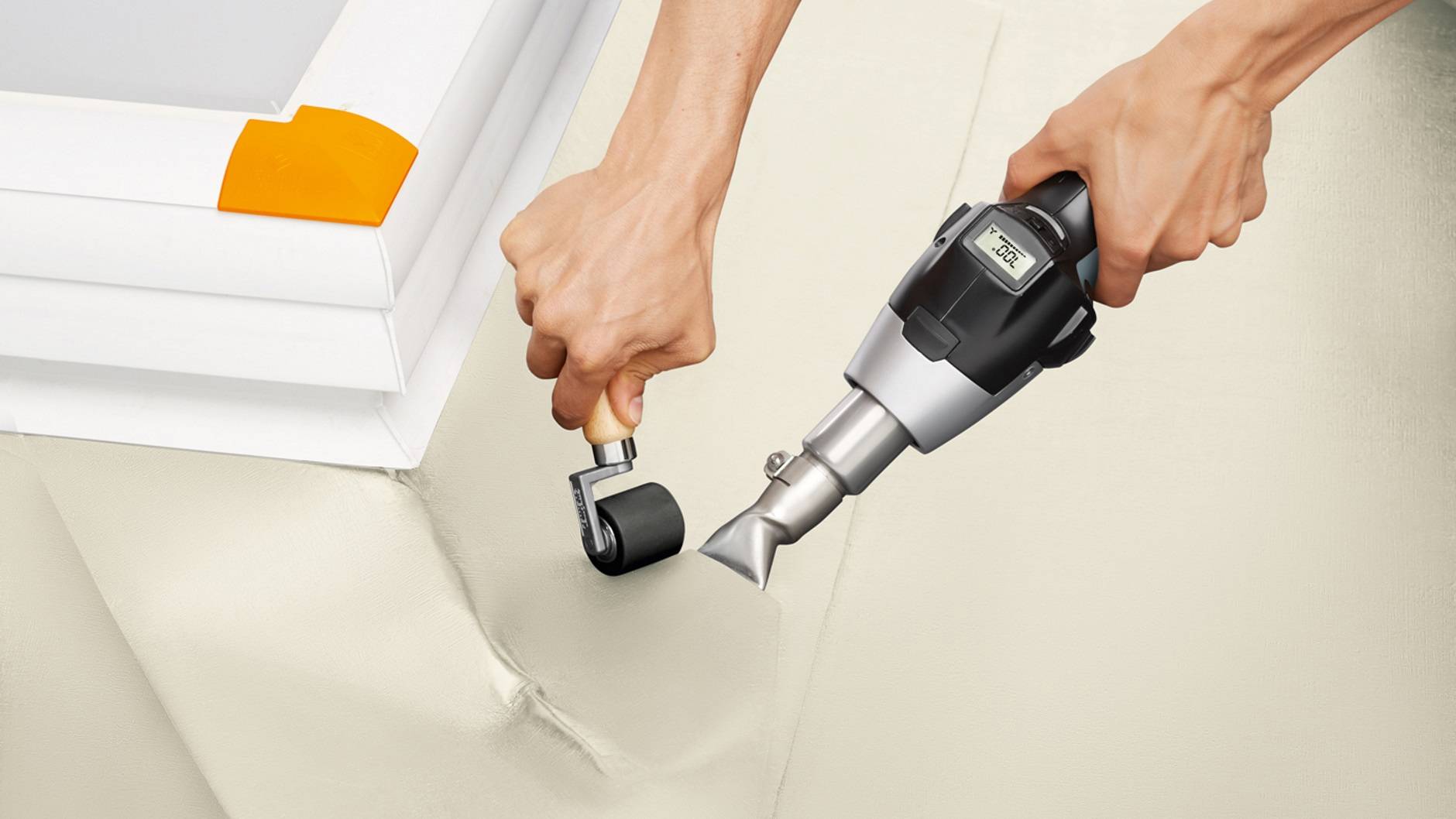 'A person is using a welding tool to attach a protective film to a roof and smoothing it with a roller.'