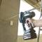 A person is holding a Makita power tool in a construction environment, likely used for cutting materials such as metals.
