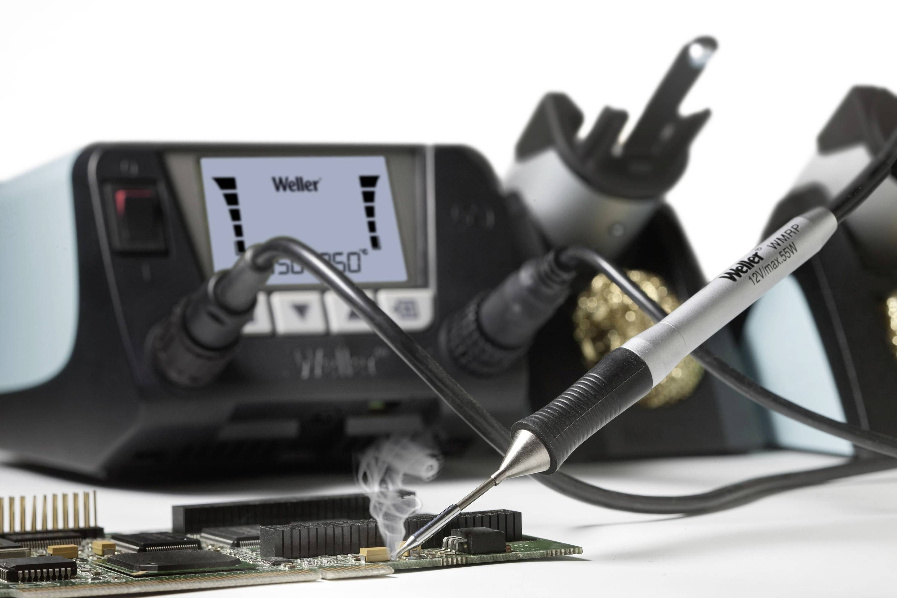 Soldering iron heats a component on a circuit board, with a soldering station featuring a temperature display in the background.