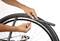 A person is changing the inner tube of a bicycle tyre. Hands are loosening the valve while the tube is being pulled over the rim.