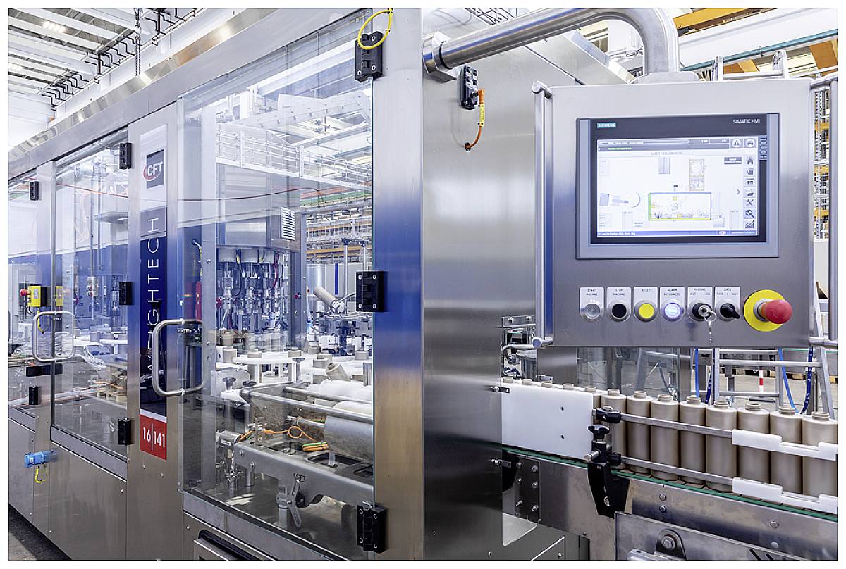 A high-quality packaging machine in an industrial hall, with a touchscreen display for control and rollers on a conveyor belt.