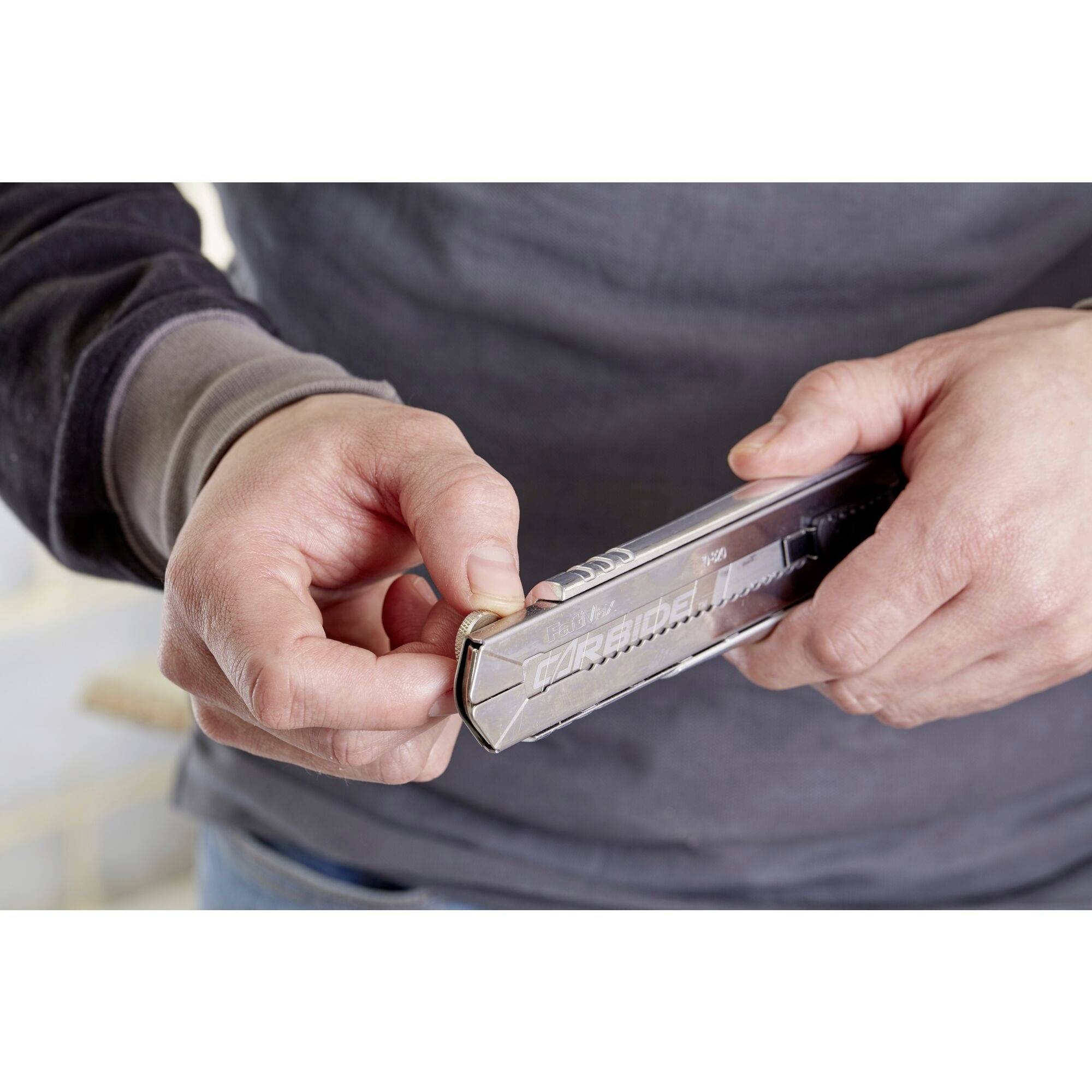 A person is holding a silver, rectangular spirit level and adjusting it. Their hands are securing the spirit level to support the measuring process.