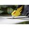 A hand wearing a black glove is using a yellow utility knife to cut a white material.