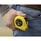 A person is holding a yellow 8m measuring tape in their hand and putting it into their jeans pocket.