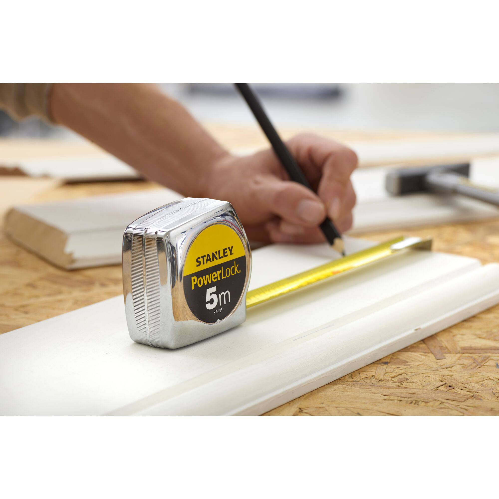 A hand is drawing on a wooden board, with a tape measure showing 5 m.
