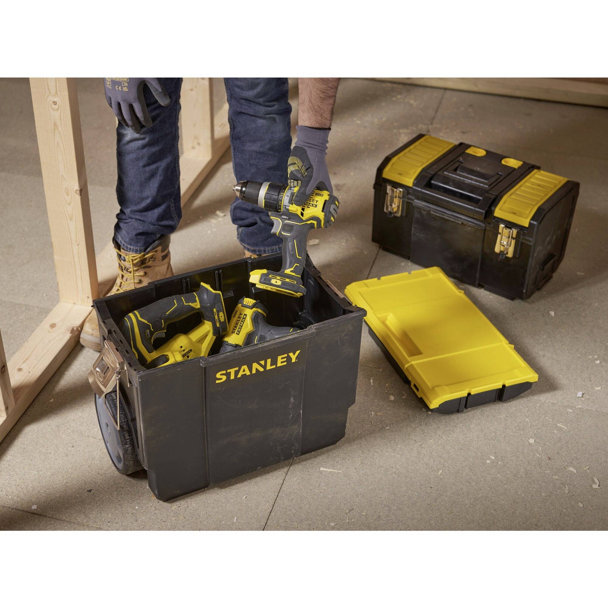 An open toolbox with a logo displays various power tools, including a yellow drill. A closed box is visible in the background.